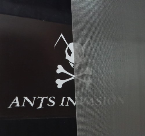 Gros plan d'une grille d'aération fine avec le logo Ants Invasion visible dessous.