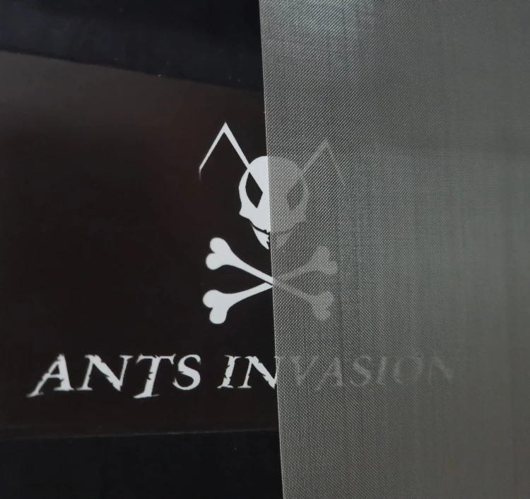Gros plan d'une grille d'aération fine avec le logo Ants Invasion visible dessous.